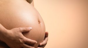 uma mulher grávida, com as mãos na barriga, o que significa sonhar com gravidez