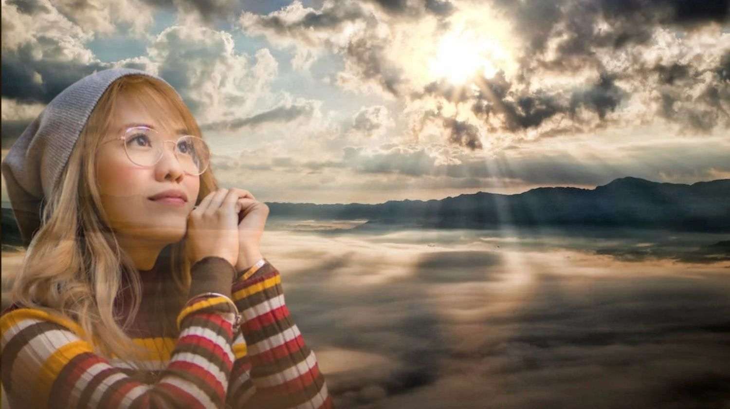 mulher olhando para o horizonte, um céu ensolarado, fazendo uma Oração ao Mentor Espiritual