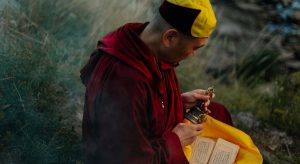 monge sentado com um sino recitando mantras budistas