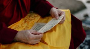 monge budista lendo papel simbolizando o questionamento de que Mantras São Perigosos