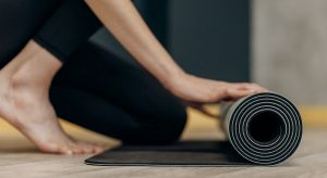 mulher na sua casa estendendo tapete simbolizando O Que é Yoga Restaurativa