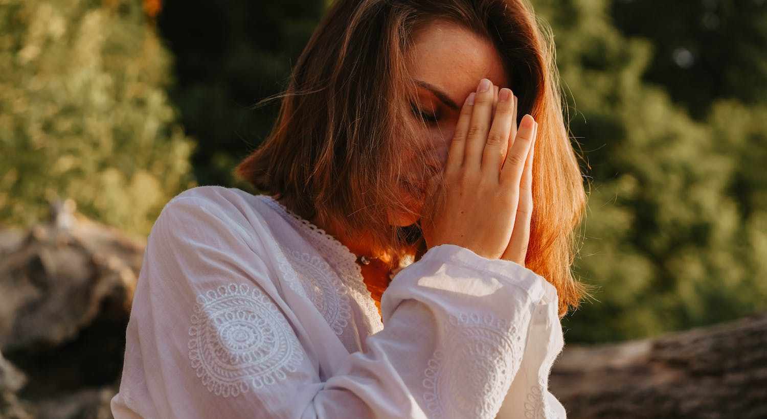 mulher com os olhos fechados com as mãos coladas meditando representando O Que é Uma Pessoa Com Espiritualidade