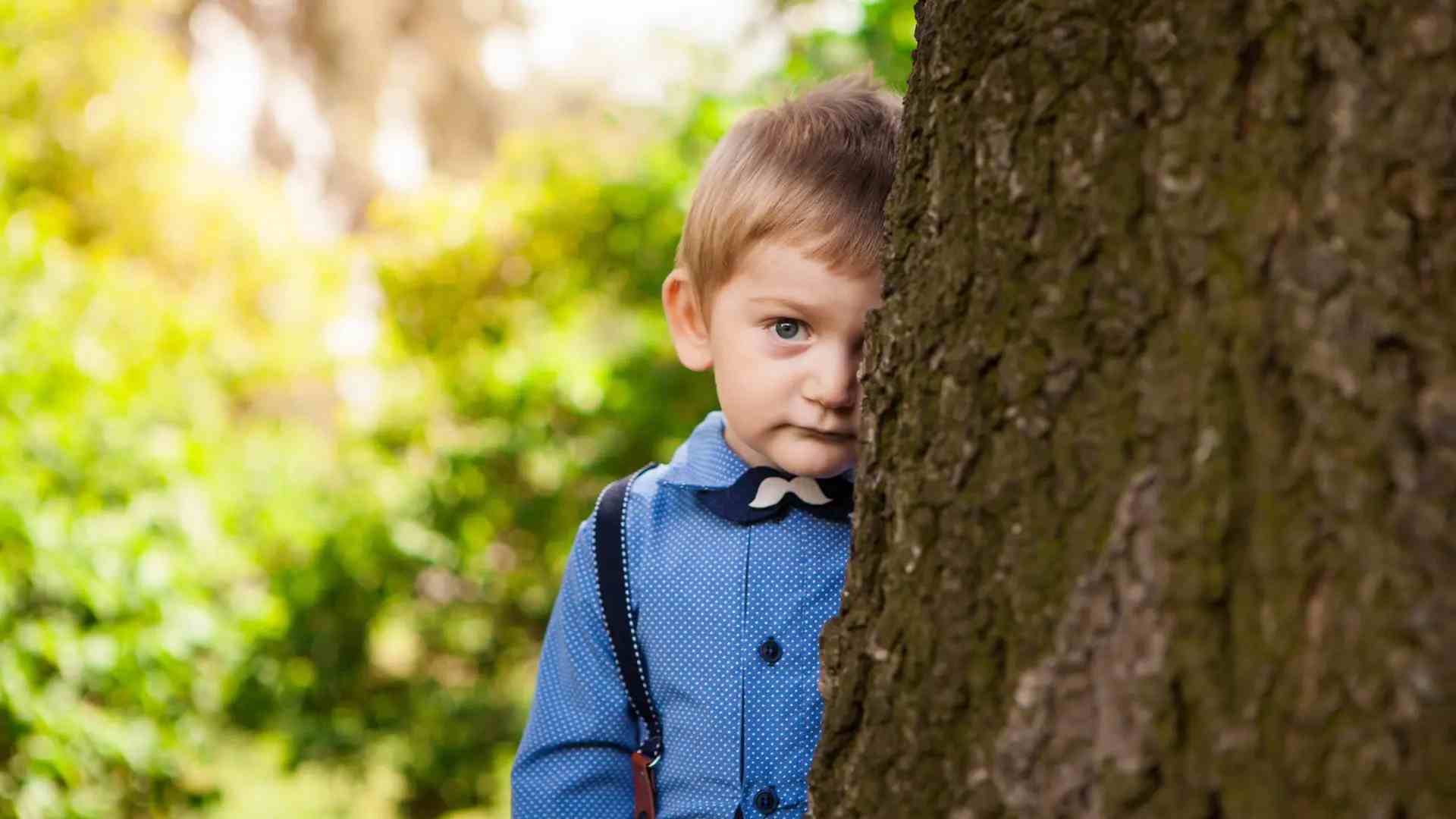 imagem de uma Criança Tímida e Retraída se escondendo atrás da árvore
