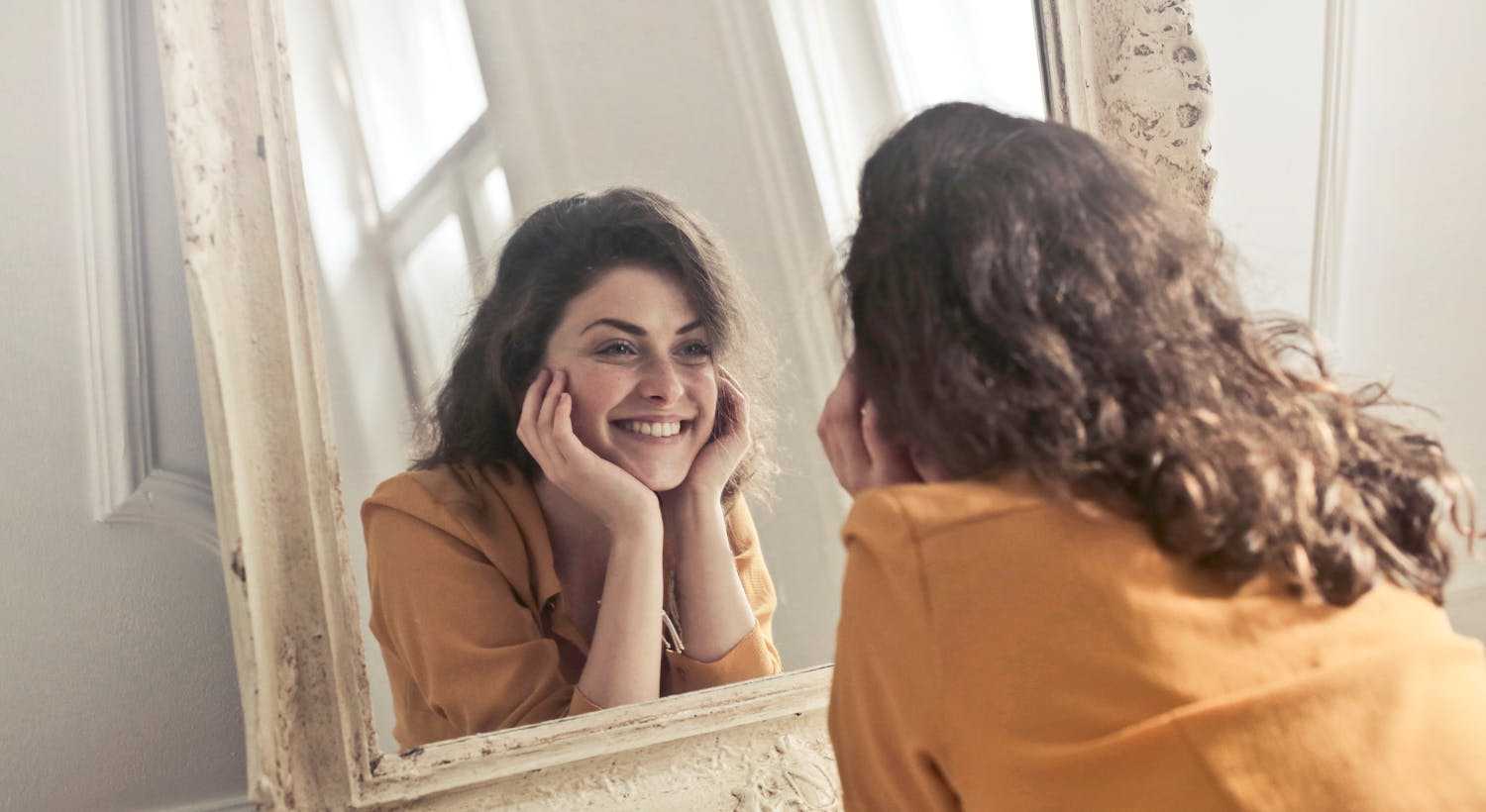 uma mulher sorrindo olhando no espelho sobre como ser uma pessoa mais leve